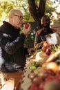 Retired man enjoying smell of fresh natural apples at farmers market