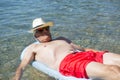 Retired man floating on bed in sea water Royalty Free Stock Photo