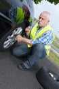 Retired man has to change punctured wheel Royalty Free Stock Photo
