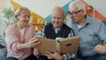 Retired men and woman watching photographs in photobook talking smiling