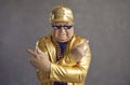 Studio portrait of cool senior man in thug life sunglasses and golden party outfit