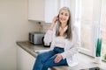 Retired people and technologies. Pleasant cheerful senior gray haired woman in white shirt and denim, talking on cell Royalty Free Stock Photo