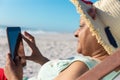 Retired senior african american woman using digital tablet while sitting on chair at beach Royalty Free Stock Photo