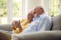 Retired Senior Couple Sitting On Sofa At Home Drinking Coffee And Watching TV Together Royalty Free Stock Photo