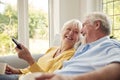 Retired Senior Couple Sitting On Sofa At Home With Remote Control Watching TV Together Royalty Free Stock Photo