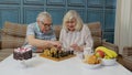 Retired senior couple talking drinking tea, playing chess in modern living home room lounge together Royalty Free Stock Photo
