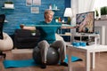 Retired senior man sitting on fitness swiss ball in living room doing wellness fitness workout Royalty Free Stock Photo