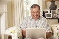 Retired Senior Man Sitting On Sofa At Home Using Laptop Royalty Free Stock Photo