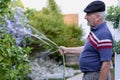 Retired senior man watering plants in the backyard of his garden