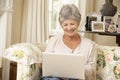 Retired Senior Woman Sitting On Sofa At Home Using Laptop Royalty Free Stock Photo
