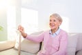 Retired woman with her wooden walking stick at home. Happy senior woman relaxing at home holding cane and looking at camera. Royalty Free Stock Photo