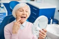 Retired woman pressing on right tooth before mirror Royalty Free Stock Photo
