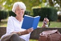 retired woman reading book on bench Royalty Free Stock Photo