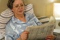 Retired woman reading newspaper before sleeping