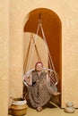 Retired woman sits in wicker swing