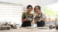 Retired woman and young woman holding handicraft crockery and smiling at camera. Activity, handicraft, hobbies concept