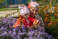 Senior woman in a flower garden with a baby,retired woman with baby in blooming garden in autumn Royalty Free Stock Photo