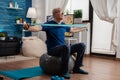 Retiree senior man sitting on swiss ball in living room doing healthcare fitness exercises Royalty Free Stock Photo