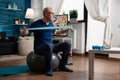 Retiree senior man sitting on swiss ball in living room doing healthcare fitness exercises Royalty Free Stock Photo