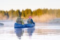 retirees rowing a canoe in early spring in the early morning. seniors lifestyle. Morning landscape, fog by the morning
