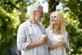 Retirement Leisure. Smiling Senior Spouses Walking Outdoors And Drinking Takeaway Coffee Royalty Free Stock Photo