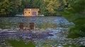 Retirement Living - Two Muskoka chairs sitting on a rocky shore facing a calm lake with trees and a boathouse in the background