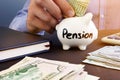 Retirement plan. Man is putting dollar banknote in a piggy bank with sign pension. Royalty Free Stock Photo