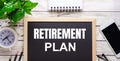 RETIREMENT PLAN written on a black background near pencils, a smartphone, a white notepad and a green plant in a pot Royalty Free Stock Photo