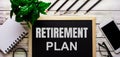 RETIREMENT PLAN is written in white on a black board next to a phone, notepad, glasses, pencils and a green plant Royalty Free Stock Photo