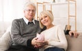 Retirement savings. Senior couple holding piggybank at home Royalty Free Stock Photo