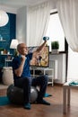 Retirement senior man sitting on aerobics swiss ball raising hand streching arm muscle Royalty Free Stock Photo