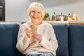 Retirement. Senior woman sitting at home drinking hot tea laughing cheerful enjoying evening Royalty Free Stock Photo