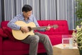 Retirement seniors sitting on a sofa playing guitar happily in the living room