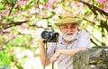 Retirement travel. Capturing beauty. Photographer in blooming garden. Senior man hold professional camera. Photography