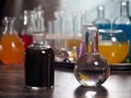 Retort with clear water and a dark bottle. Laboratory glassware with colorful liquids on the table Royalty Free Stock Photo