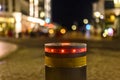 Retractable bollard with a red warning light as a barrier to a pedestrian area at night in Bansin, Germany. In the background you