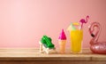 Retro aesthetic still life with orange juice, flamingo pool float and plastic toys, Summer vacation vibes concept over pink Royalty Free Stock Photo