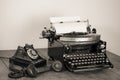 Retro aged black typewriter with paper blank,  telephone on wooden table. Vintage style sepia photo Royalty Free Stock Photo