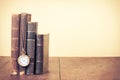 Retro aged books, pocket watch on oak wooden table. Vintage style filtered photo