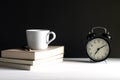 Retro alarm clock beside a cup of coffee on top the books. Royalty Free Stock Photo