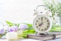 Retro alarm clock, notebook and spring flowers. Royalty Free Stock Photo