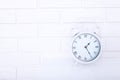 Retro alarm clock with twenty five minutes past one o`clock near brick wall on white workplace. Selective focus Royalty Free Stock Photo