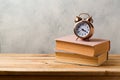 Retro alarm clock and vintage books on wooden table