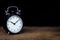 Retro alarm clock on wooden table with black background isolated Royalty Free Stock Photo