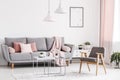 Retro armchair, grey sofa with pink pillows and coffee tables in