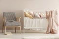 Retro armchair next to white wooden crib with pastel bedding