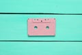 Retro audio cassette on a turquoise wooden background. Trend of minimalism. The concept of obsolete audio technology.