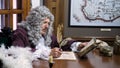 Retro baroque man with white wig holding a quill pen, sitting at antique table and thinking about paper documents