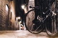 Retro bicycle in the night old city on background bokeh light flare in night architecture, vintage bike in evening street Royalty Free Stock Photo
