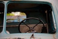 Retro black steering wheel inside old and abandoned blue truck